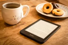 eReader on table with mug and doughnuts
